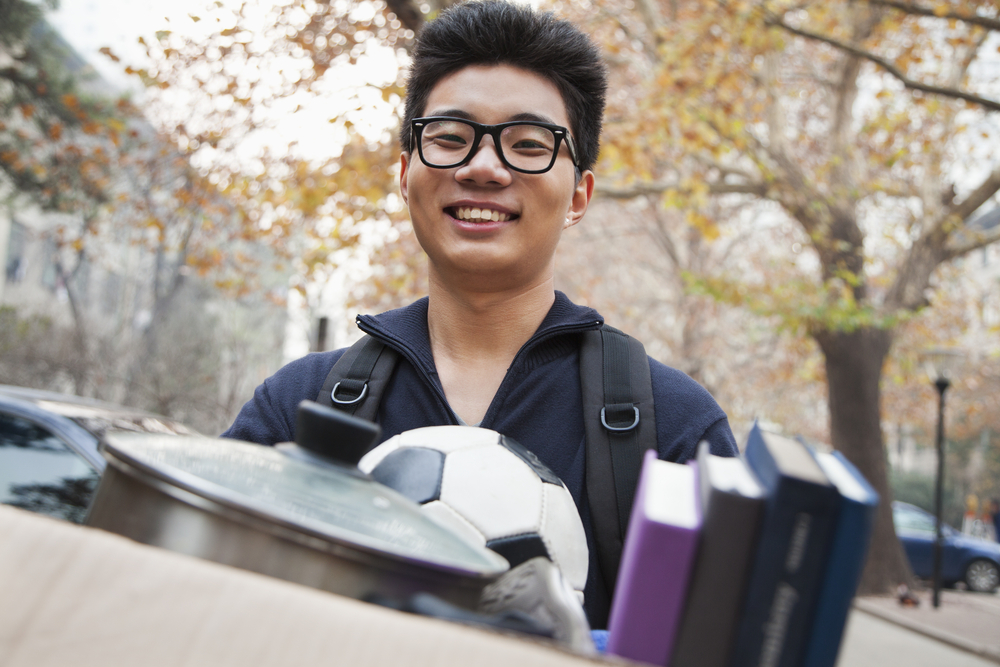 college student in front of dorm packing for storage