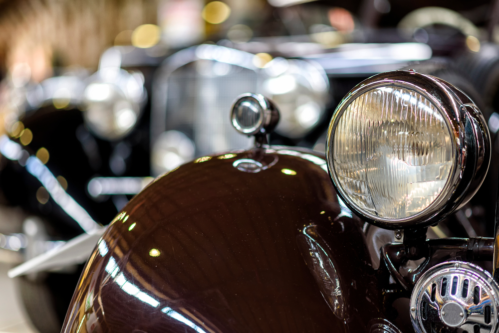 headlight of a classic car with other classic cars in the background
