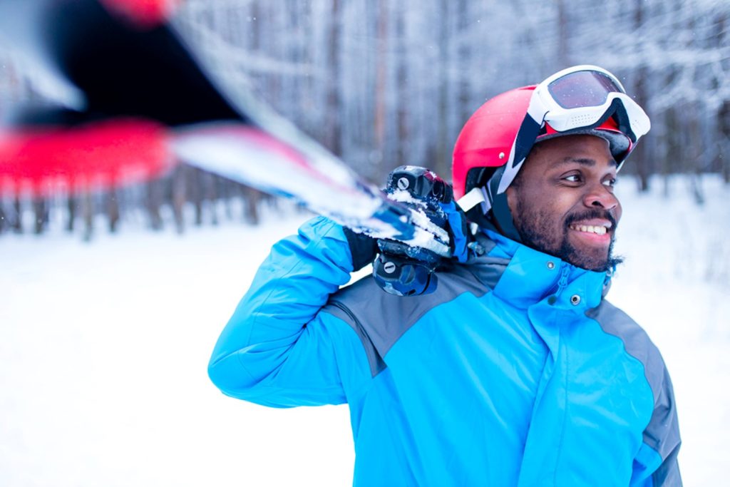 african american man holding skis in the snow