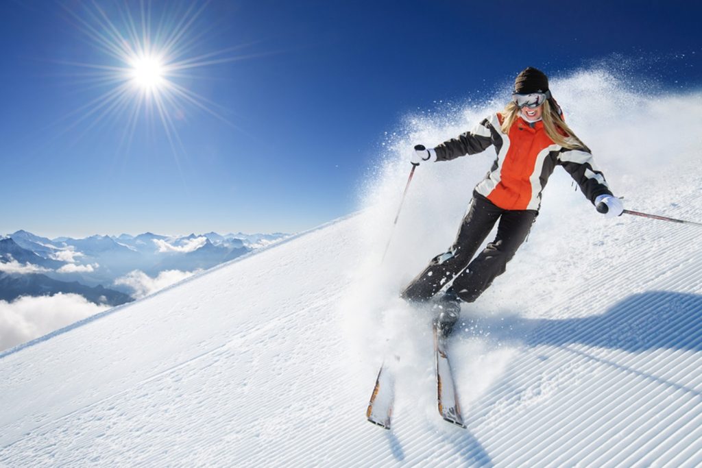 young woman skiing in the snow with sun shining
